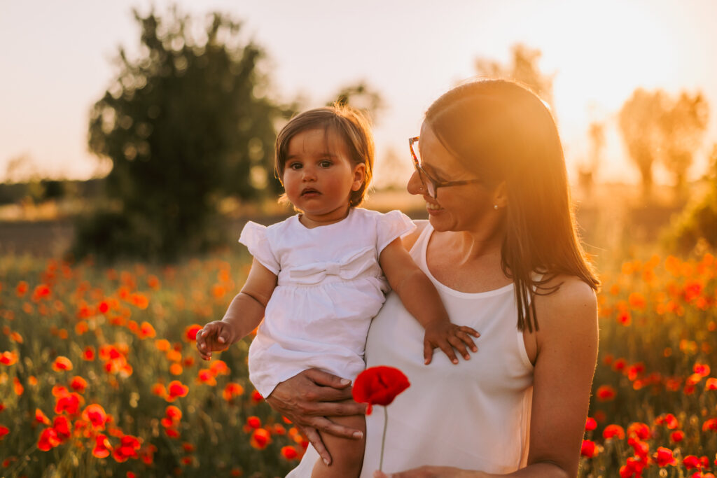 mamma e figlia che si guardano al tramonto tra i papaveri sessione fotografica