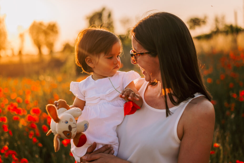 mamma e figlia che si guardano al tramonto tra i papaveri sessione fotografica